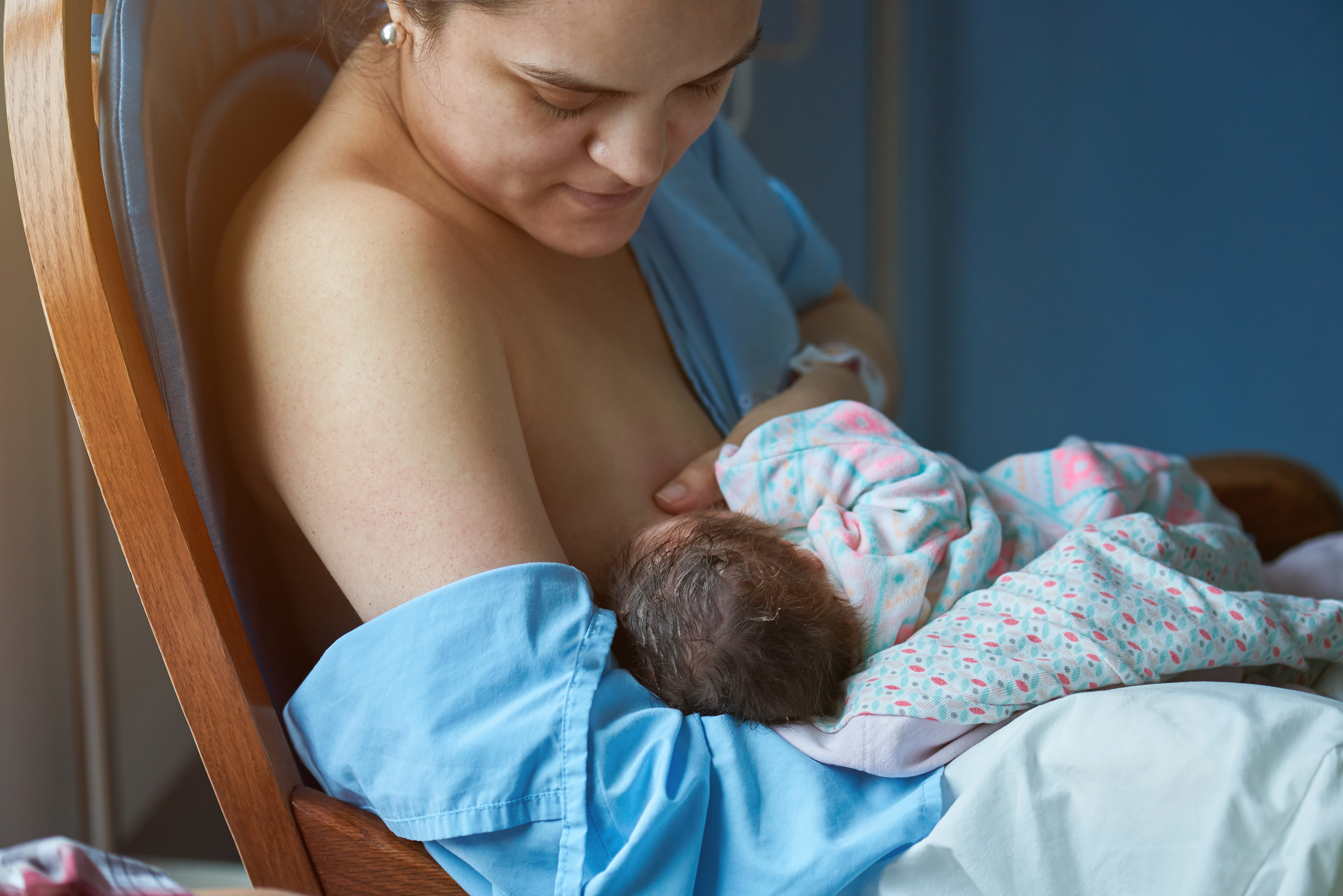 Mother sitting in a chair breastfeeding her baby.