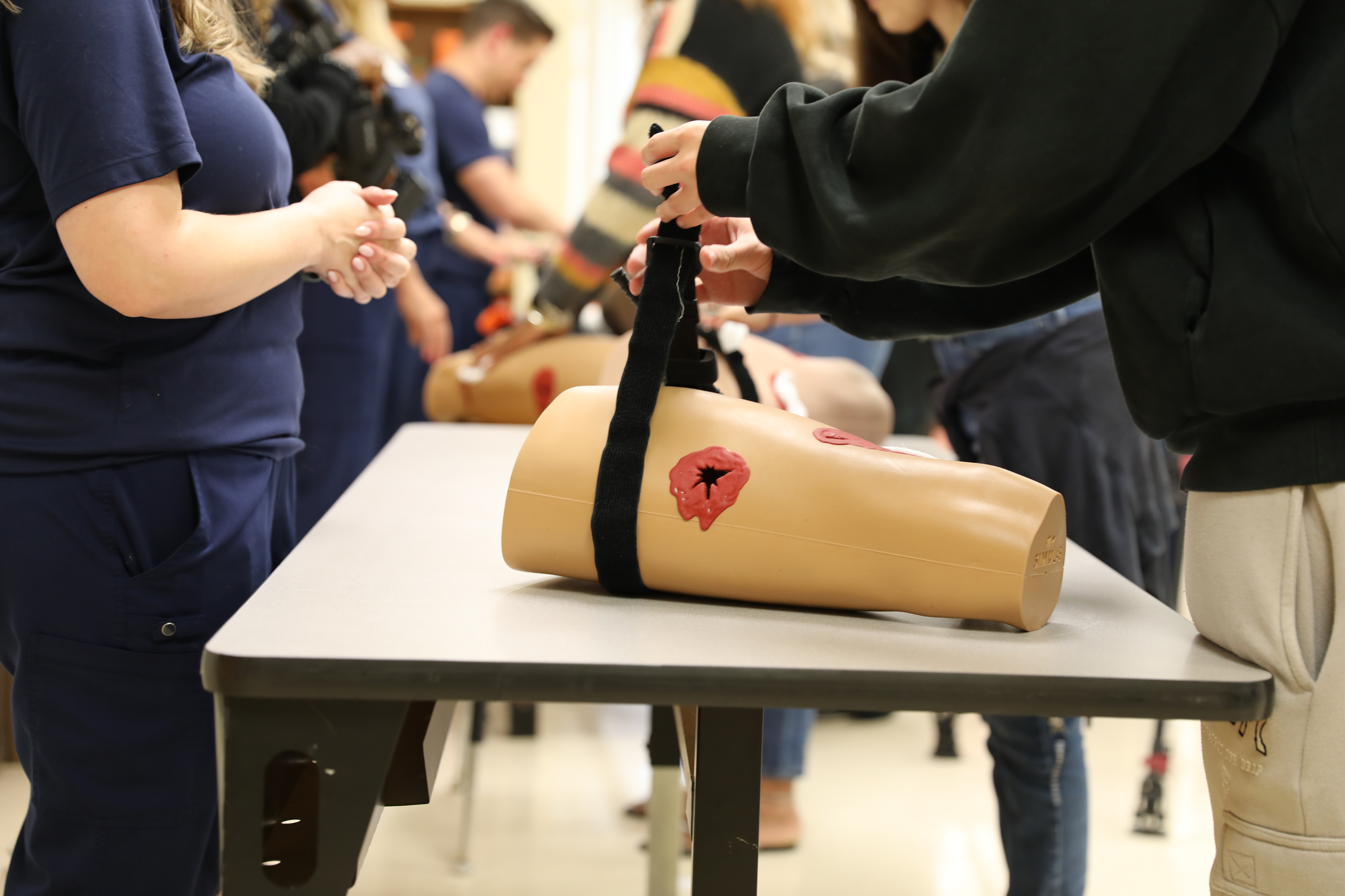 School officials training with tourniquets on dummy limbs.