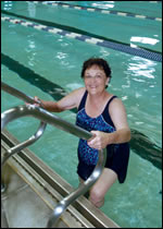 Jacque Chastain smiles while using the ladder to climb out of a swimming pool.