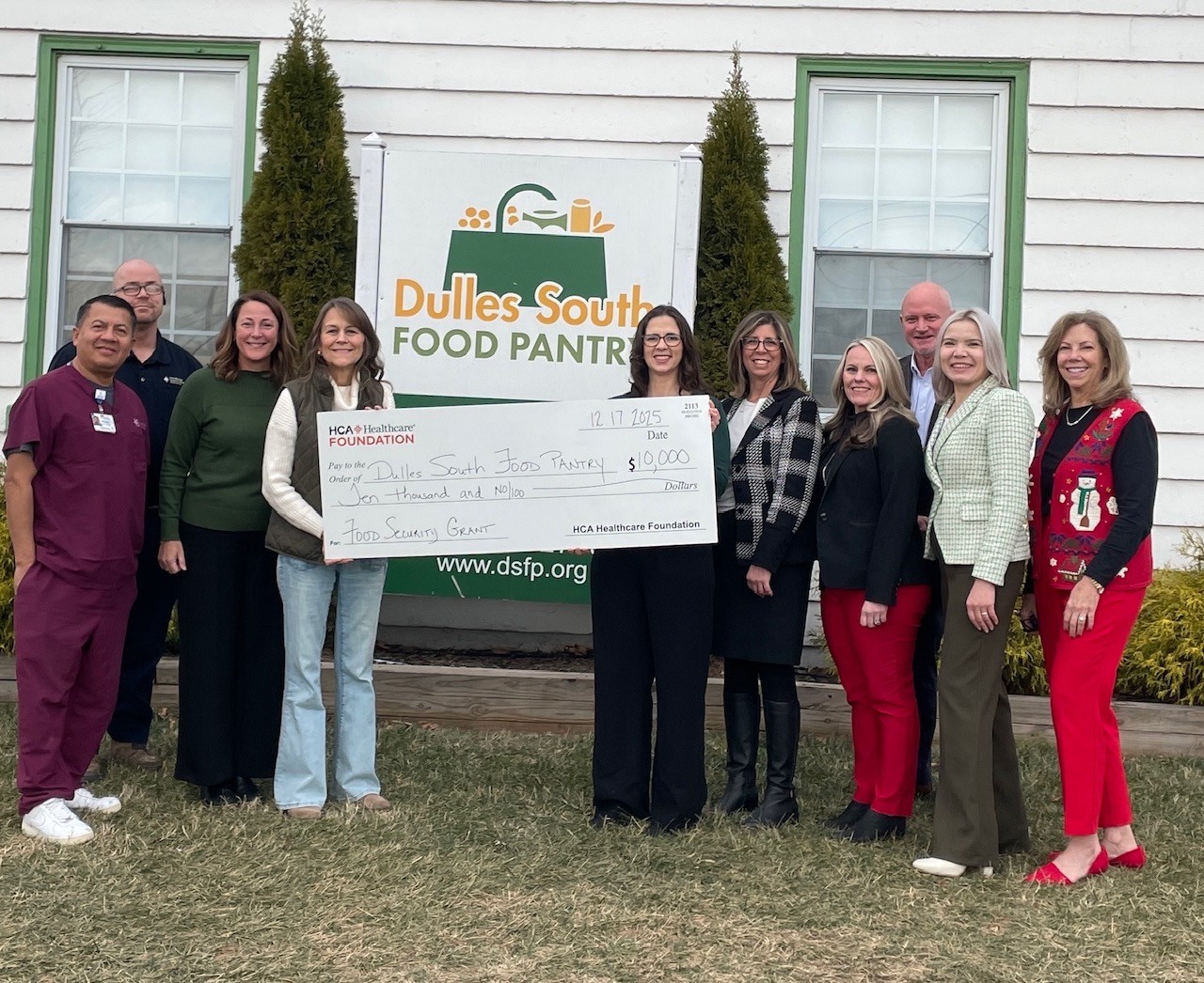HCA team members present oversized donation check outside Dulles South Food Pantry to food pantry representatives.