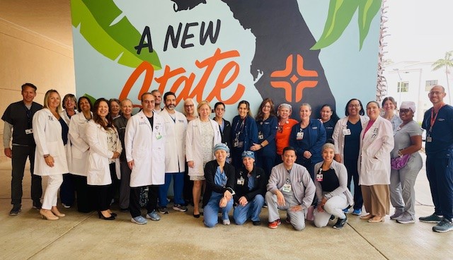 JFK Hospital Stroke Team group posing in front of a mural