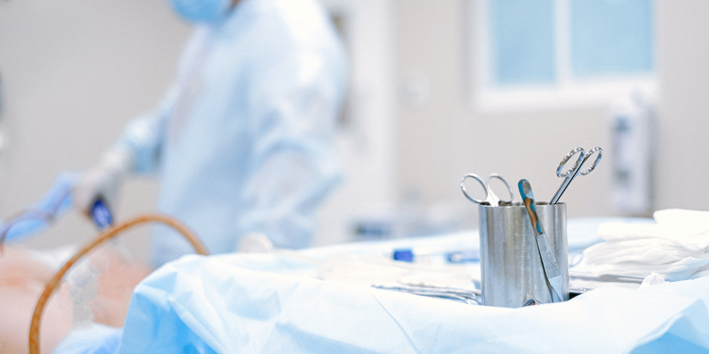 A surgeon performs a surgical procedure on a patient, with a tray and surgical instruments in the foreground.