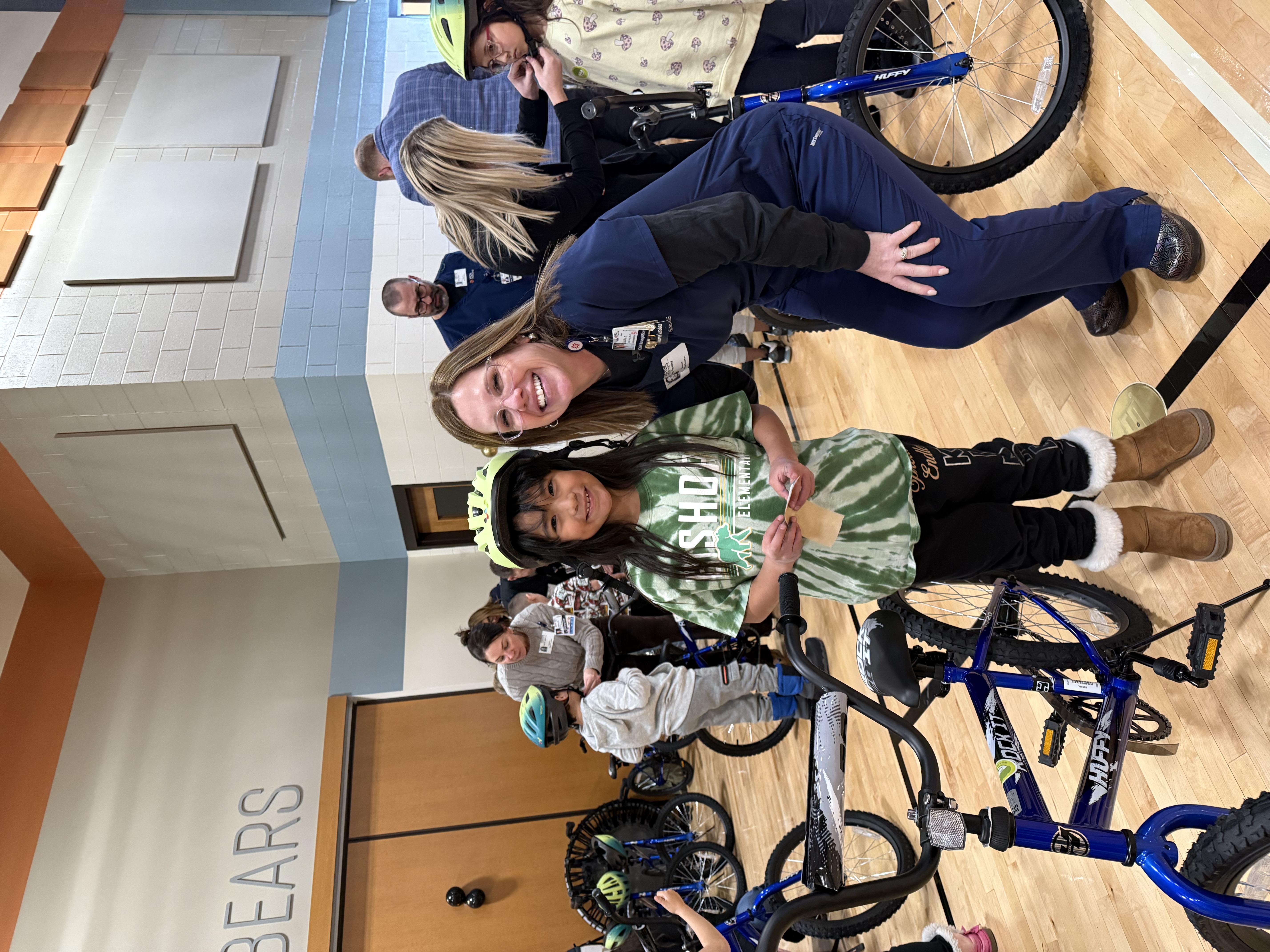 Laura Thornley, Chief Nursing Officer at HCA HealthONE Swedish, helps a grader with her new bicycle