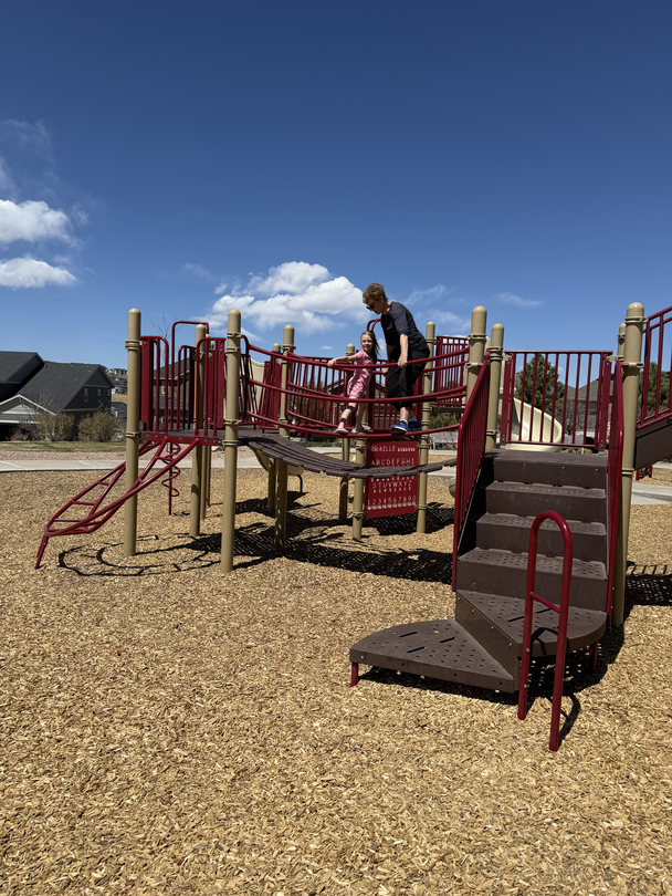 Diane playing with her grandchild on playground equipment.