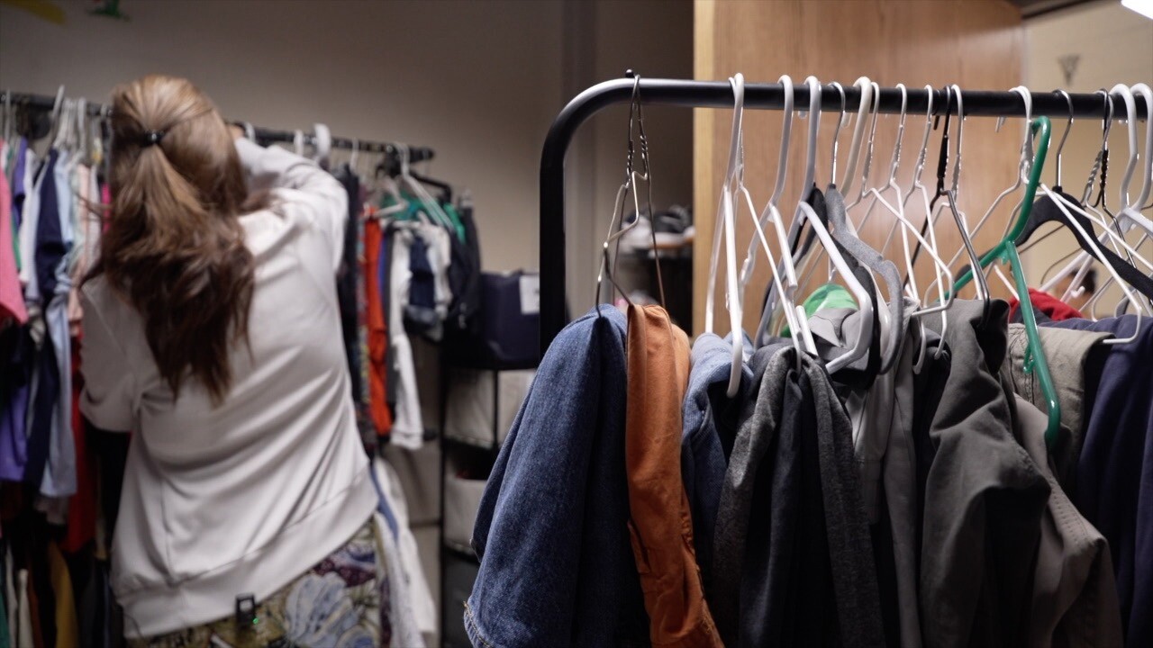 photo of a person going through a few racks of hanging clothing