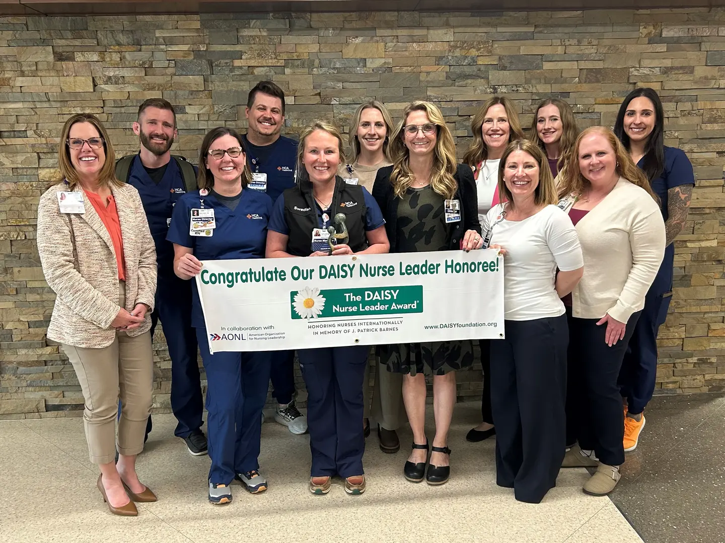 Taylor Myers and team at Swedish posing with DAISY Award banner.