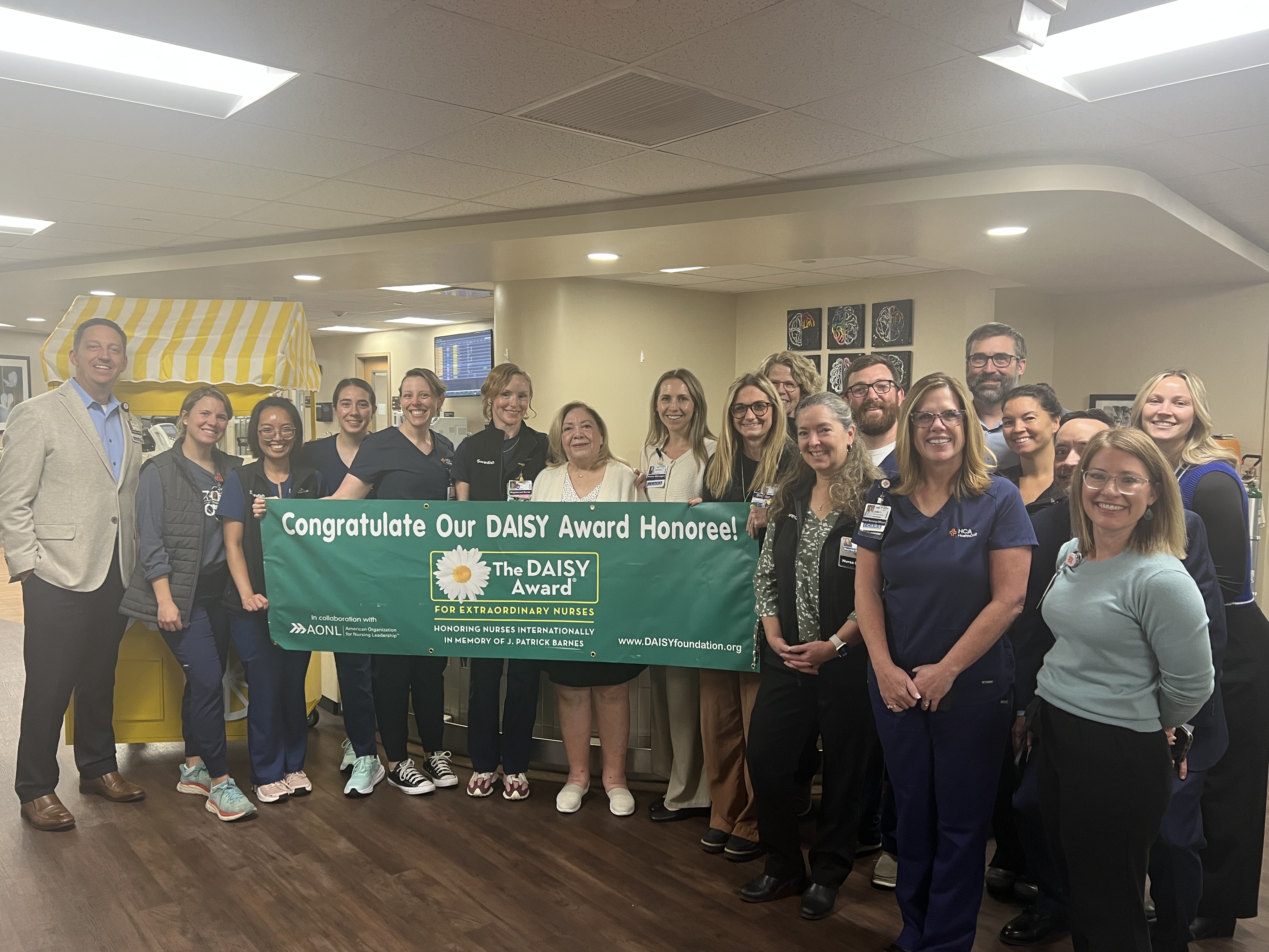 A group stands with a banner of the Daisy award.