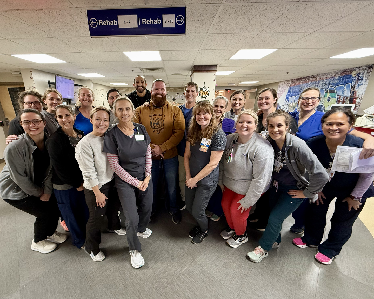 Dean smiling with hospital team in front of sign that reads 'A History of Healing.'