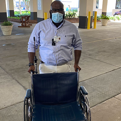 Karlis Mims standing behind a wheelchair