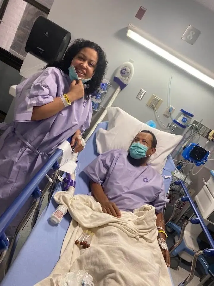 Eloisa and Adan in a hospital room wearing hospital gowns