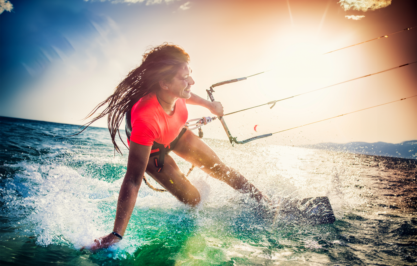 A woman smiles while windsurfing.
