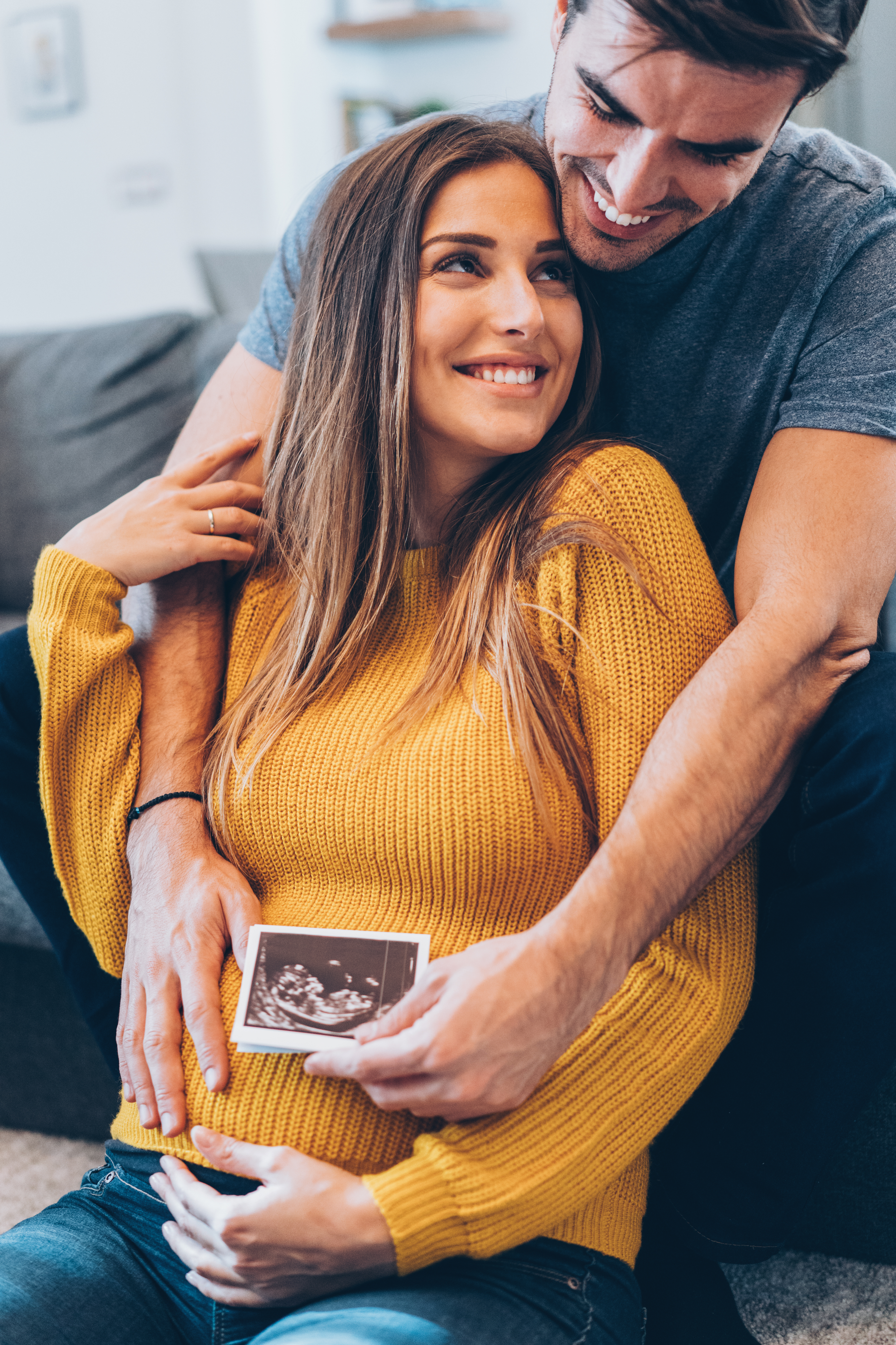 Hugging couple with baby ultrasound photo