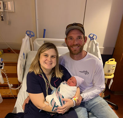 Tara Vickers and her husband smile while holding their newborn, Charlie. 