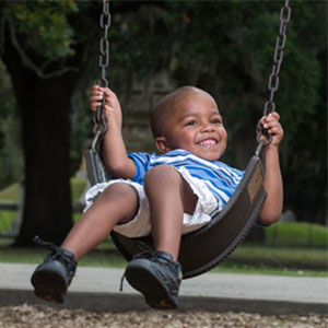 Rion Williams smiles while swinging on a swing at the park.
