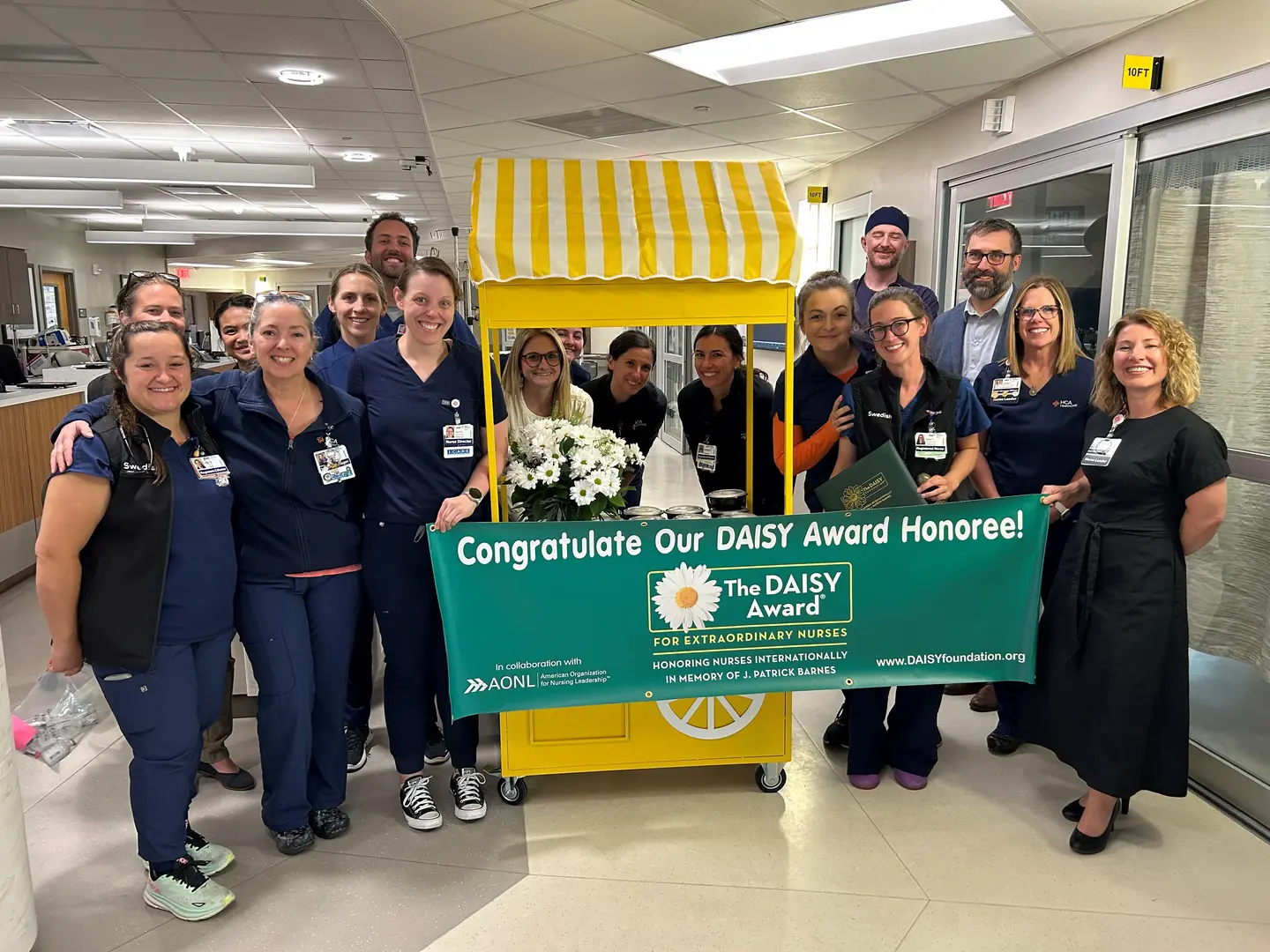 Erin Tillquist and her colleagues holding a DAISY Award winner sign.