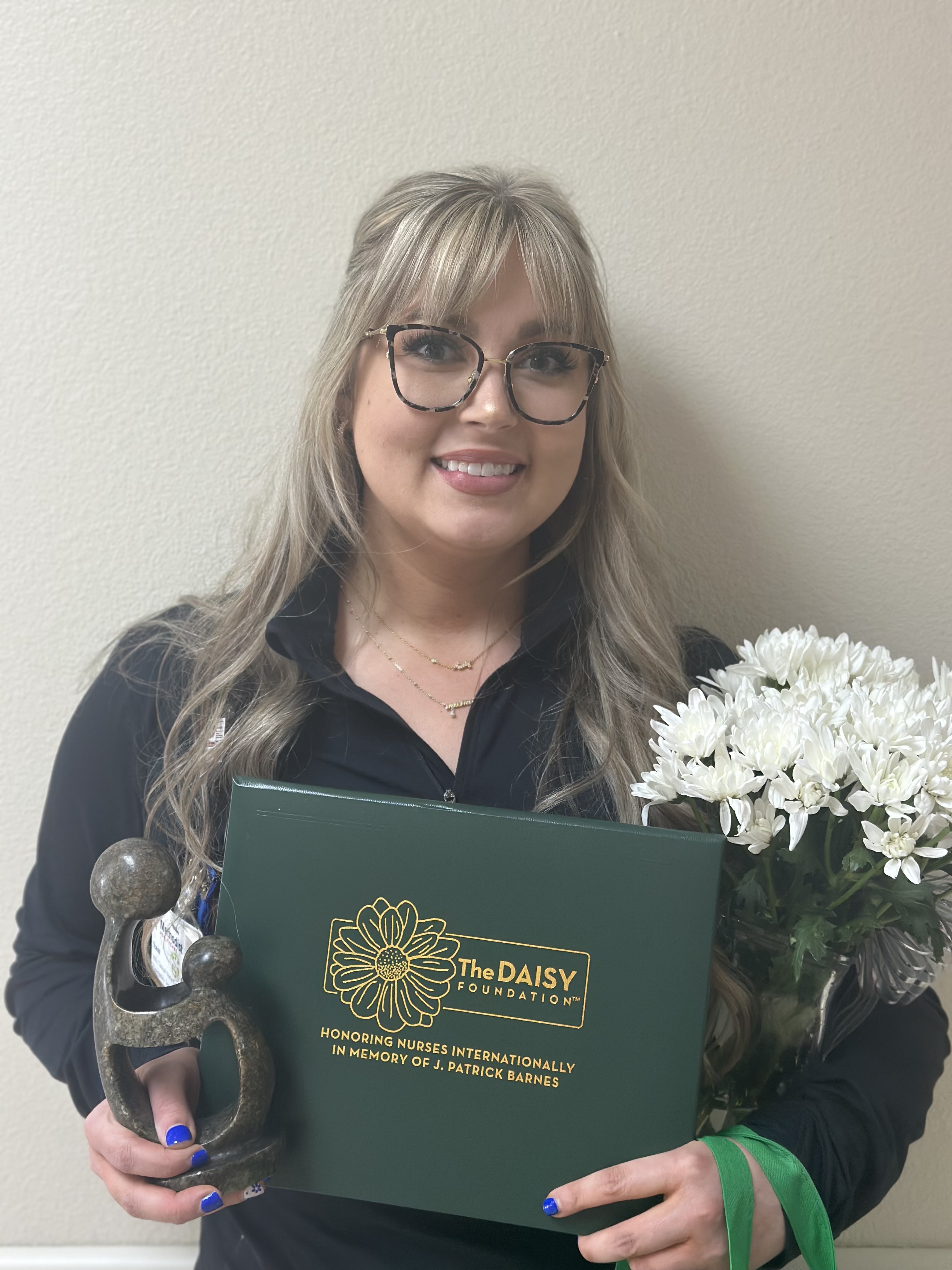Samantha Bailey smiles and holds flowers and a certificate.