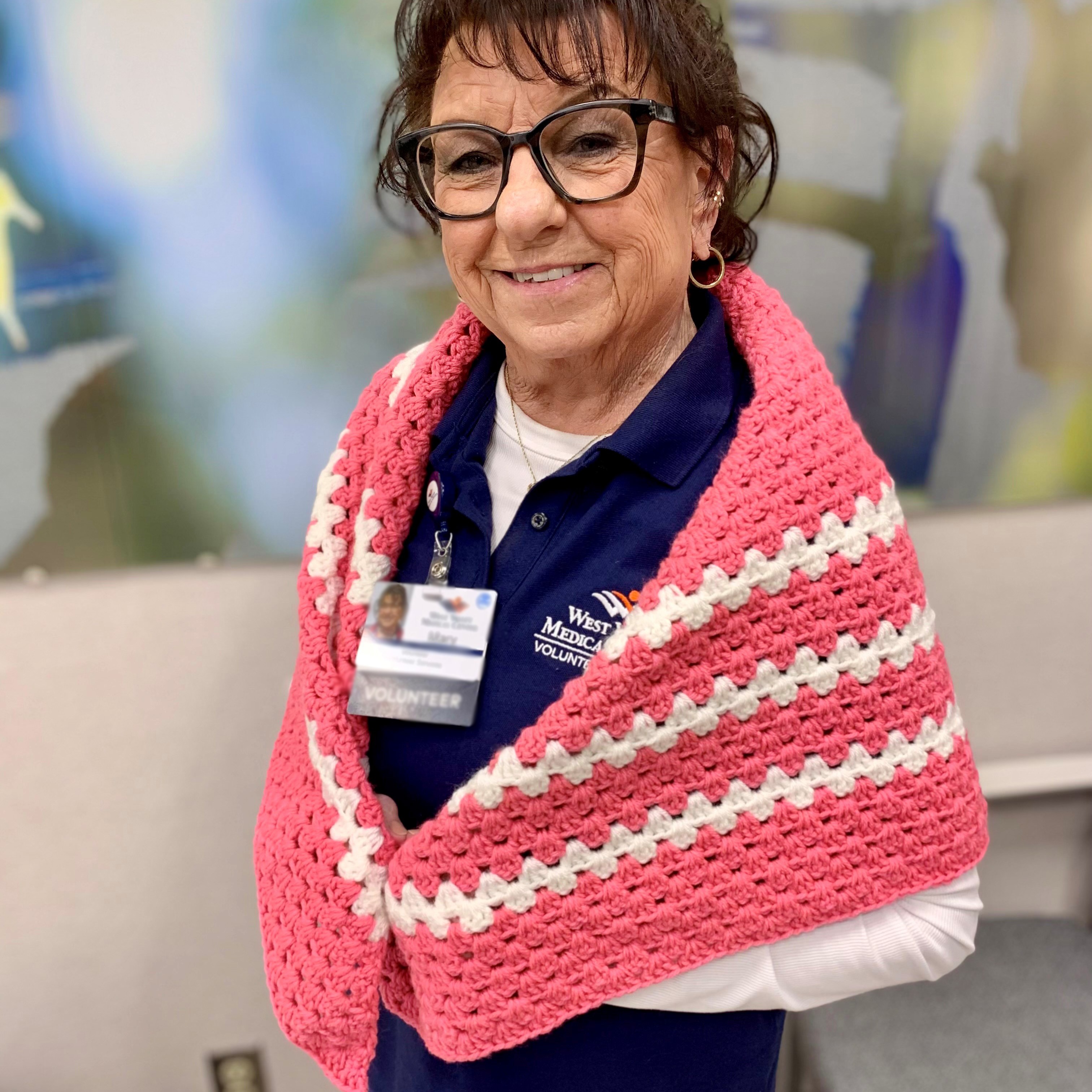 Breast cancer survivor Mary wearing eyeglasses and wrapped in a shawl. 