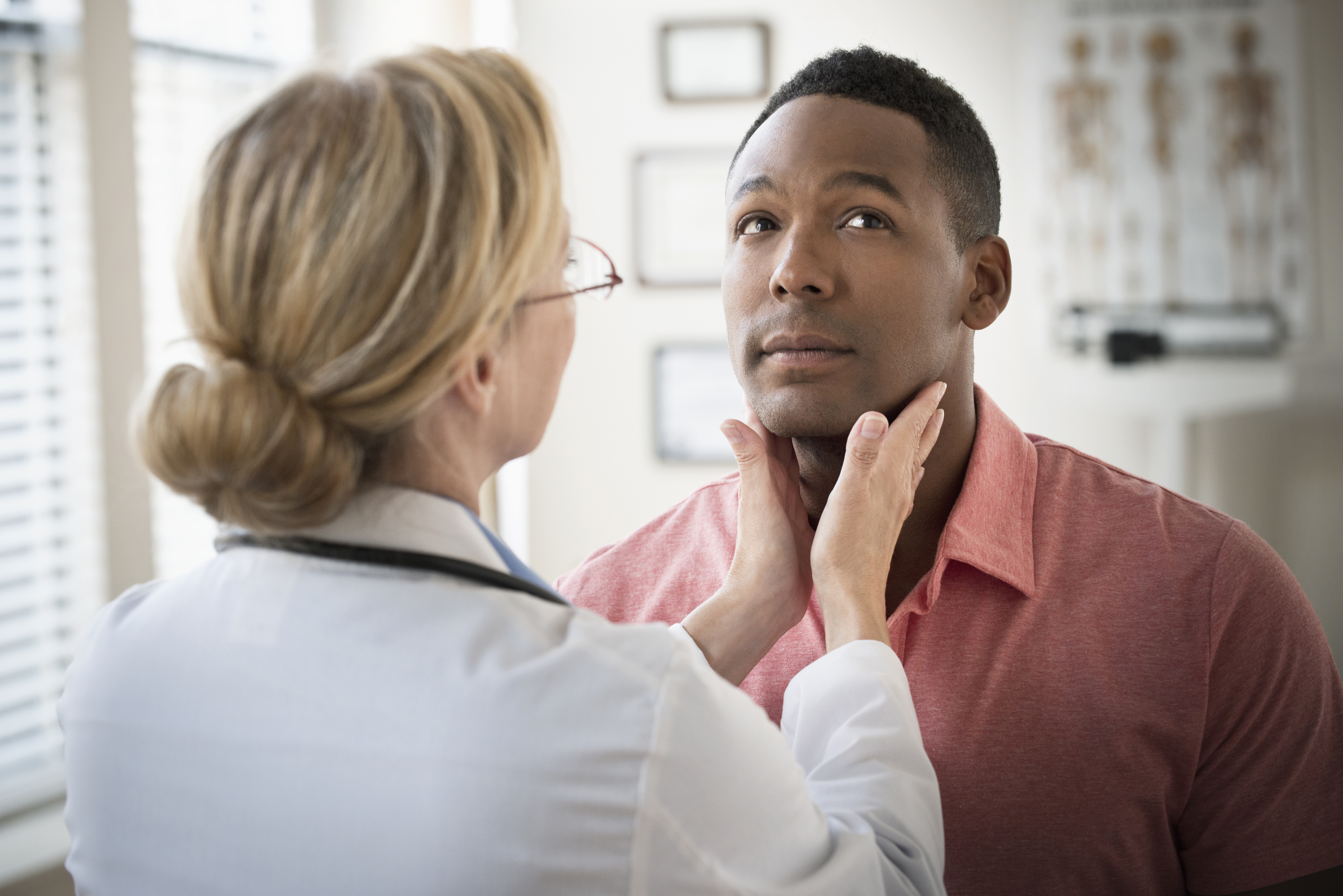 Doctor examining throat of patient in clinic