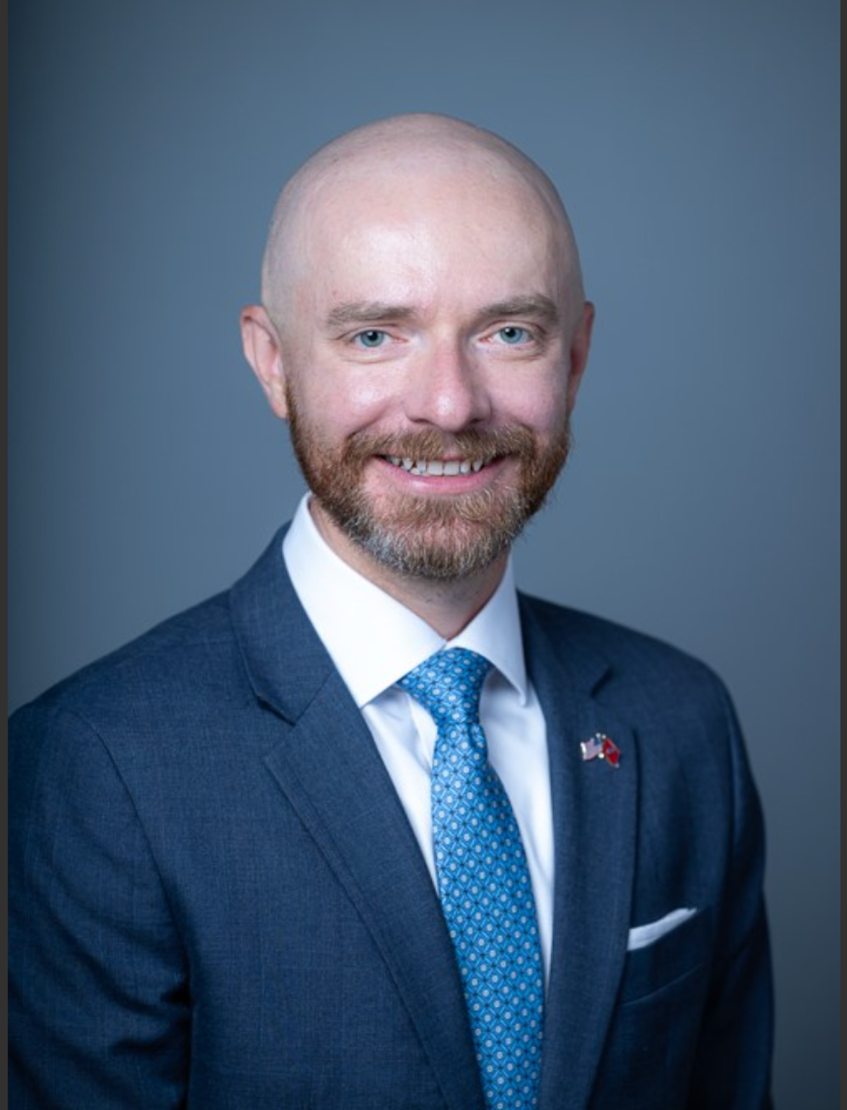 Professional headshot of Jordan Huffman, a newly appointed Board of Trustees member at TriStar Summit Medical Center. He is wearing a dark suit with a white shirt and a blue tie with a patterned design, smiling against a dark background.