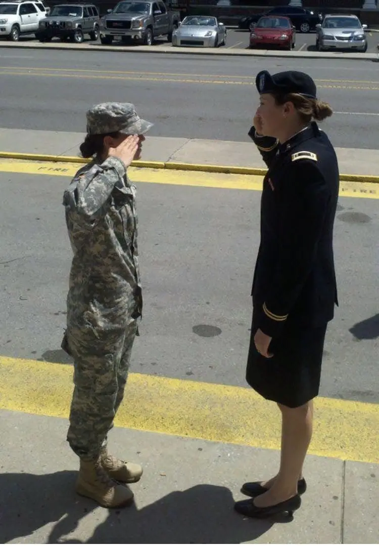 Taylor and Alex standing on a sidewalk saluting each other.
