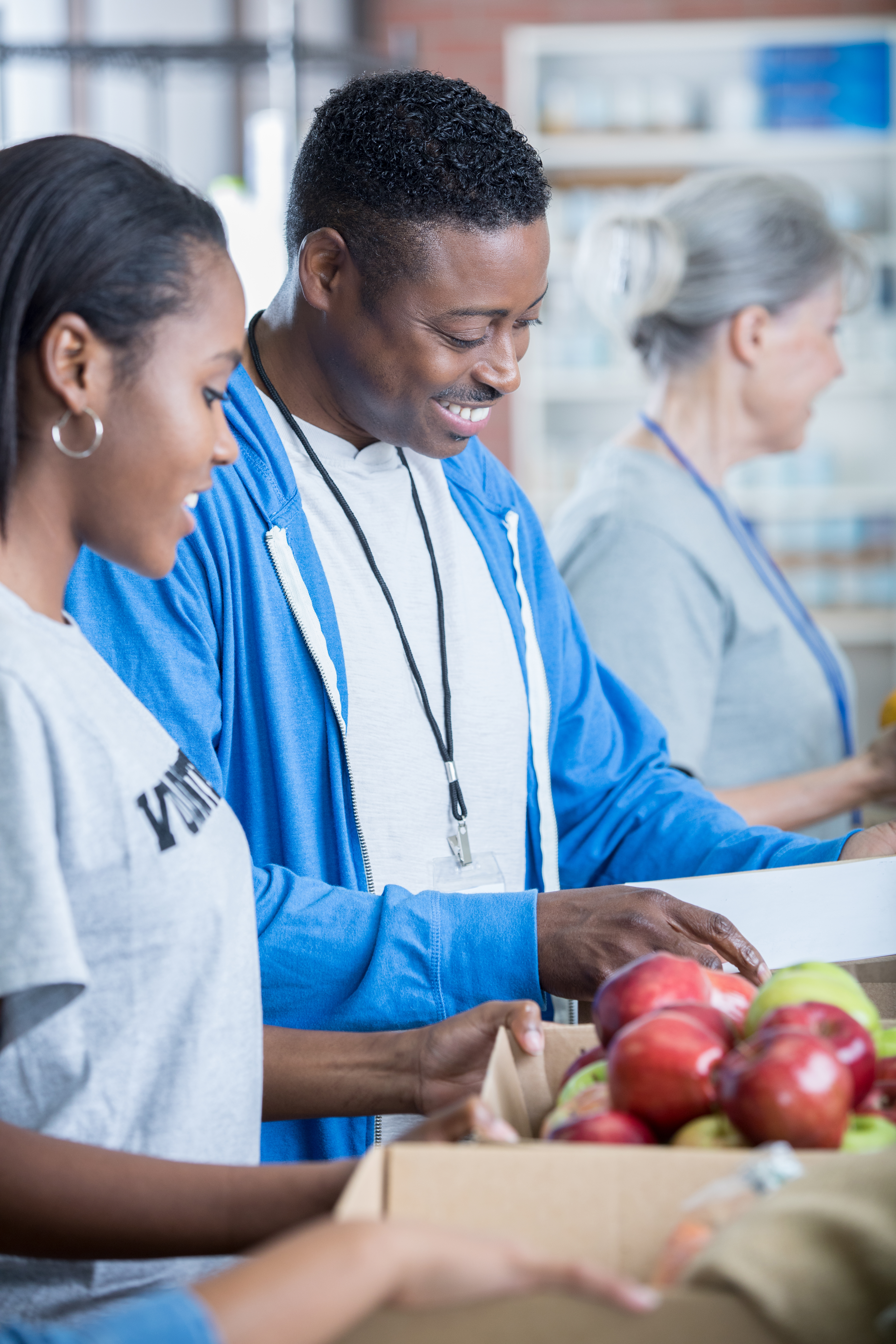 Cheerful African American father and his daughter bond as they volunteer in food bank together.