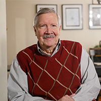 Ron is seated in an interior setting. 