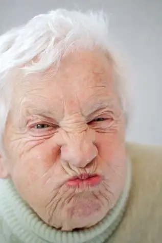 An older person scowls and scrunches their face in disapproval.