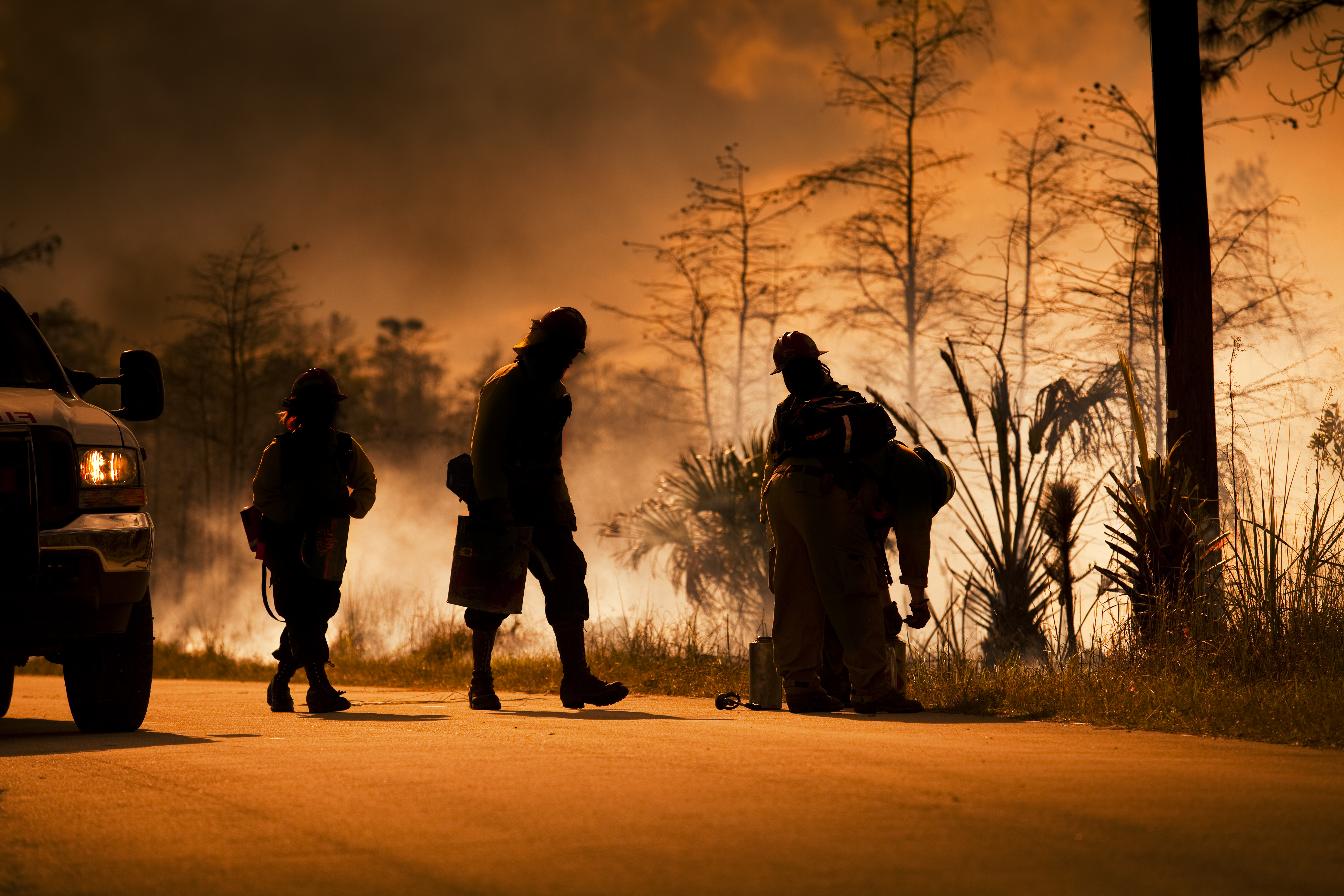Smoke and wilderness emergency - firefighters silhouetted against a wildfire