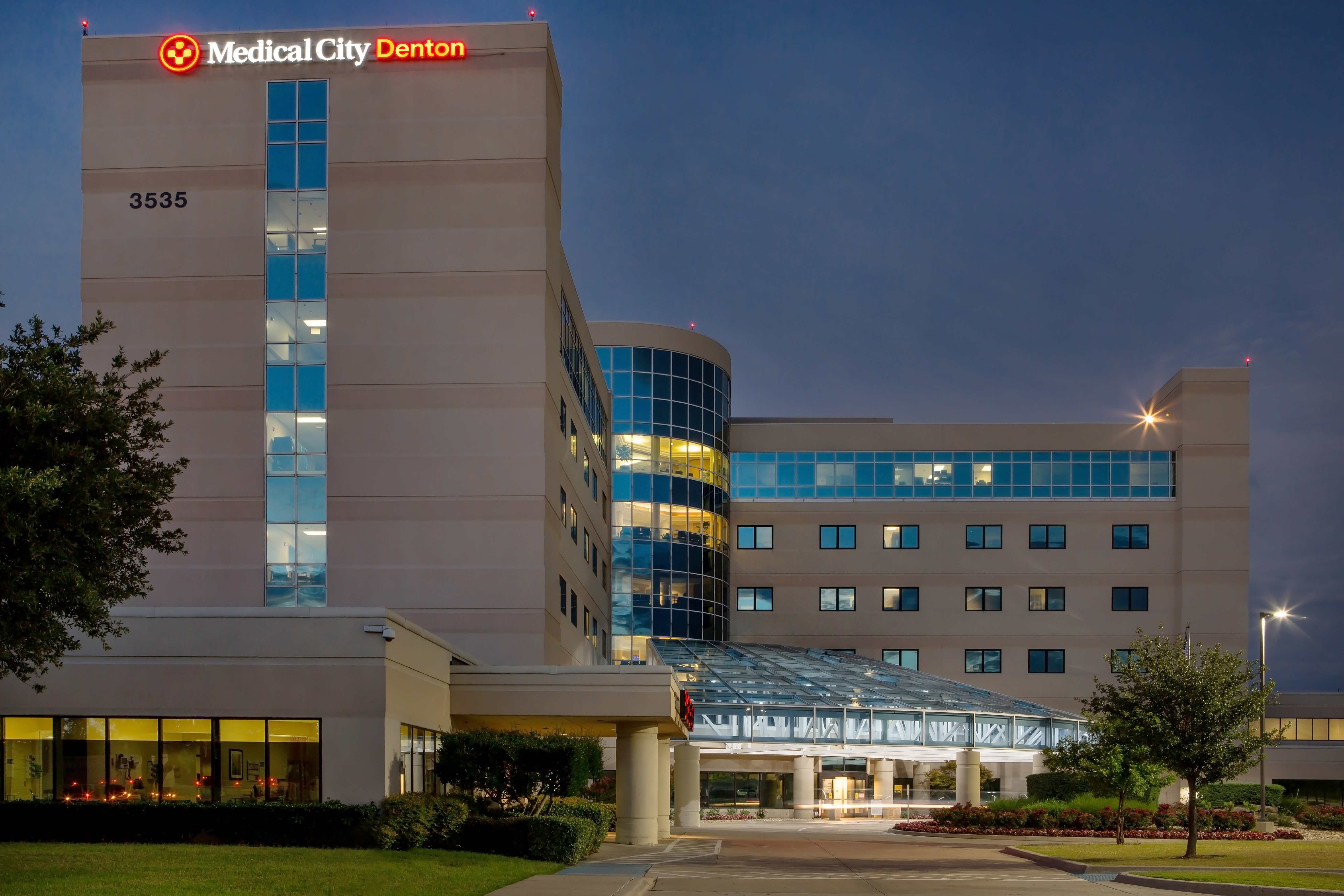 Exterior of Medical City Denton at night with signage illuminated.
