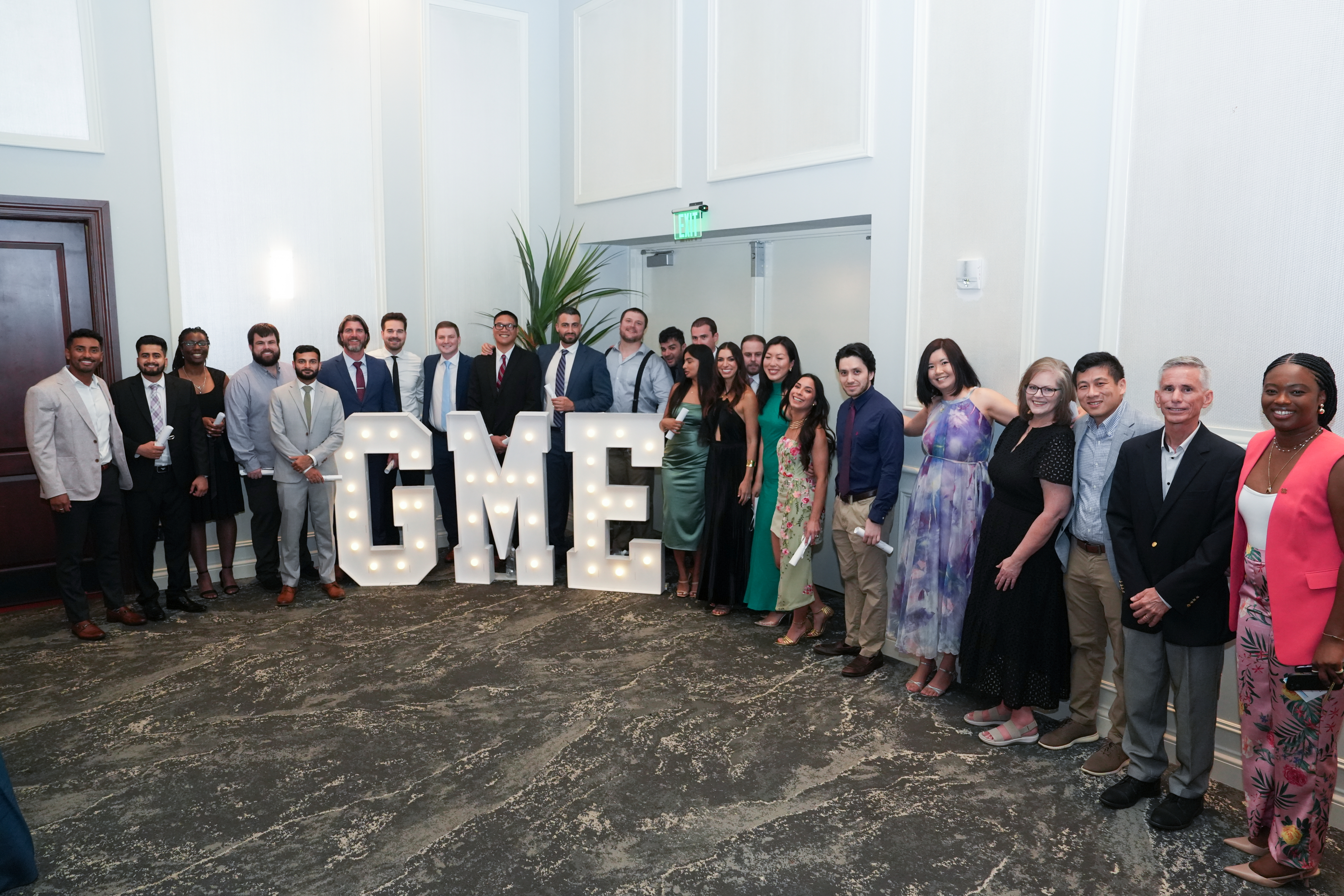 photo of a group of medical professionals standing with big "GME" letters