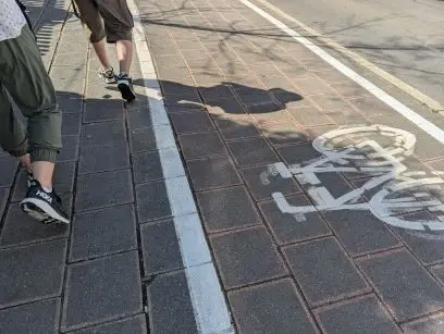 A sidewalk with people walking on it.