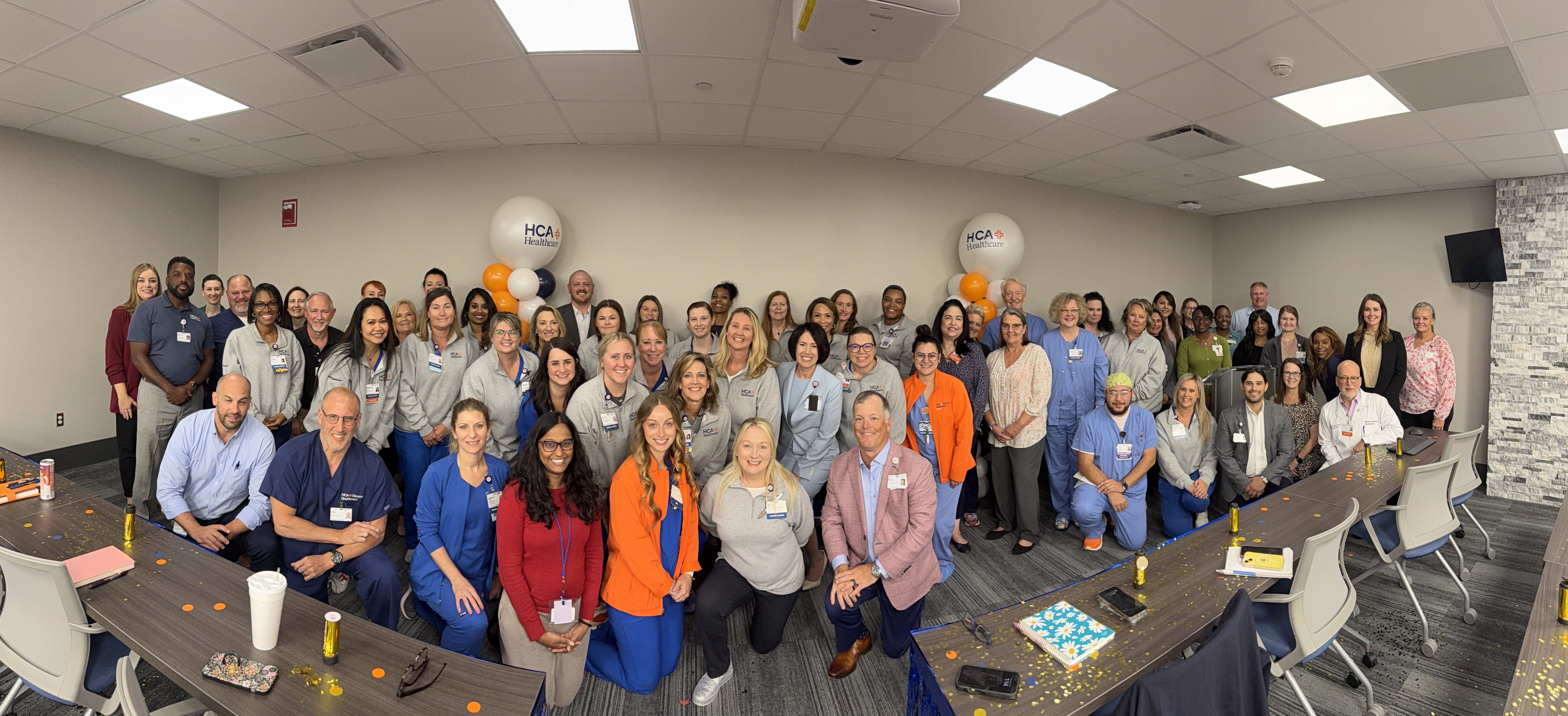 wide angle photo of a room full of people smiling in at the camera