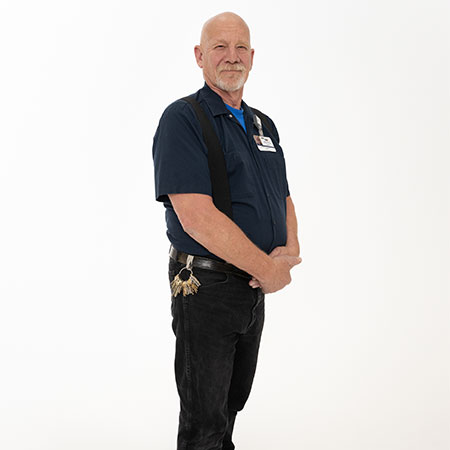 Smiling senior man in worker's uniform and heart patient Joe with his hands crossed in front of him. 