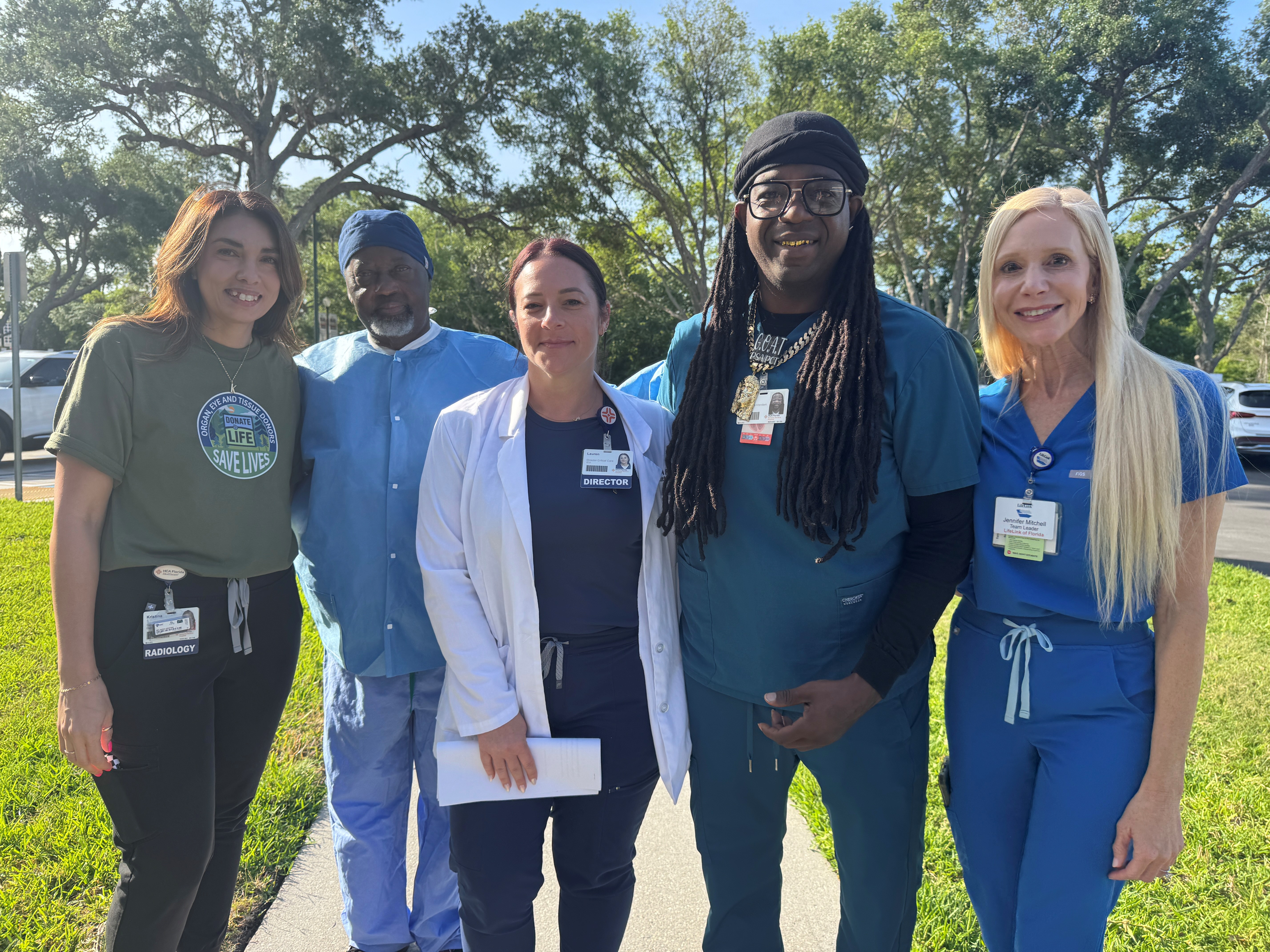 5 nurses stand together smiling outdoors
