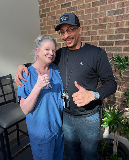 Dawn Normoyle and Jose Mercado smile while hugging and giving two thumbs up.