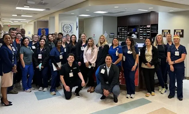 The Methodist Hospital Texsan ICU unit poses for a group photo in front of the hospital logo.