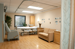 A patient room with a bed, futon, and a reclining chair. 
