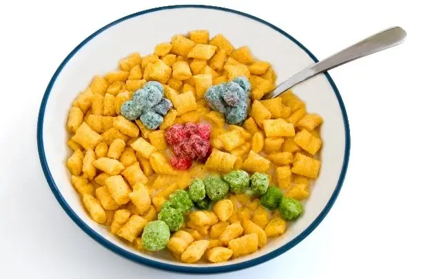 A bowl of breakfast cereal, with different colors of cereal making a sad face.