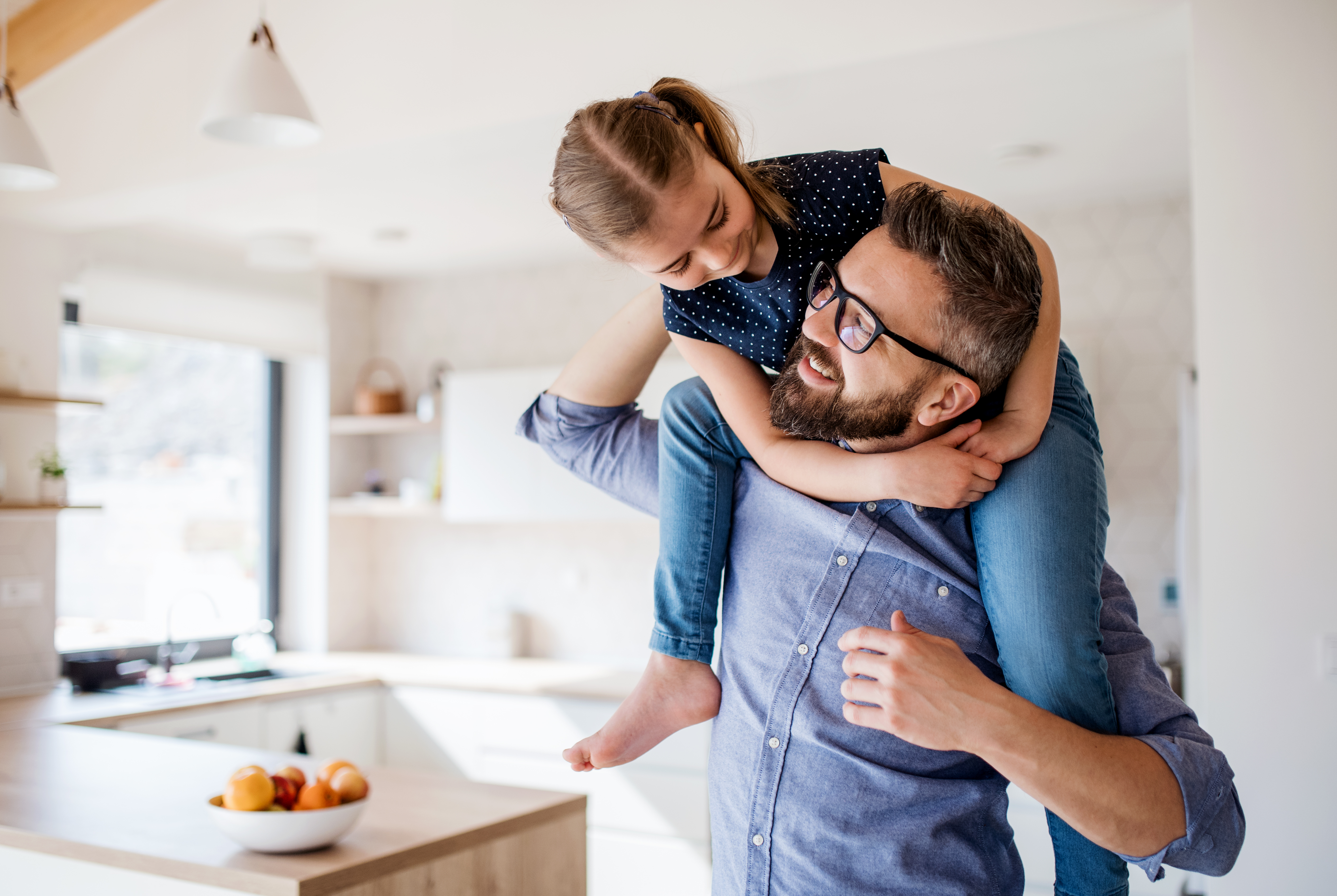 Father giving piggyback ride to daughter in the kitchen.