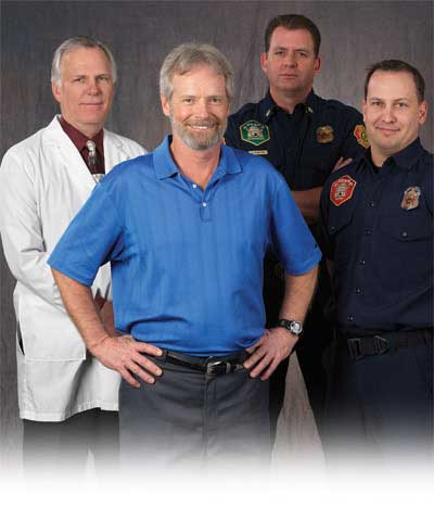 Keith Newport smiles while standing with several emergency response and medical professionals.