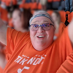 Della Burwell smiling while she celebrates with her arms up in the air.