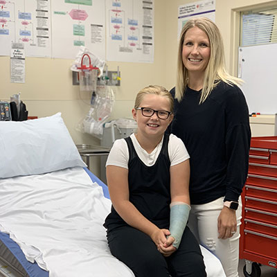 Melissa and Ava Feser smile while sitting in a patient exam room at the ER.
