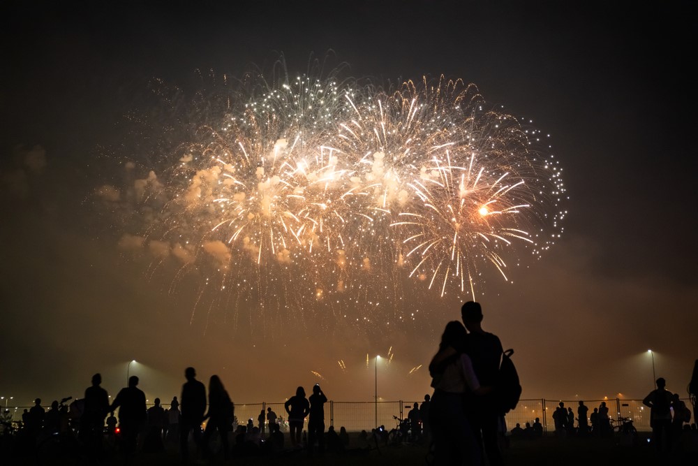A silhouette of people watching fireworks in the night sky.