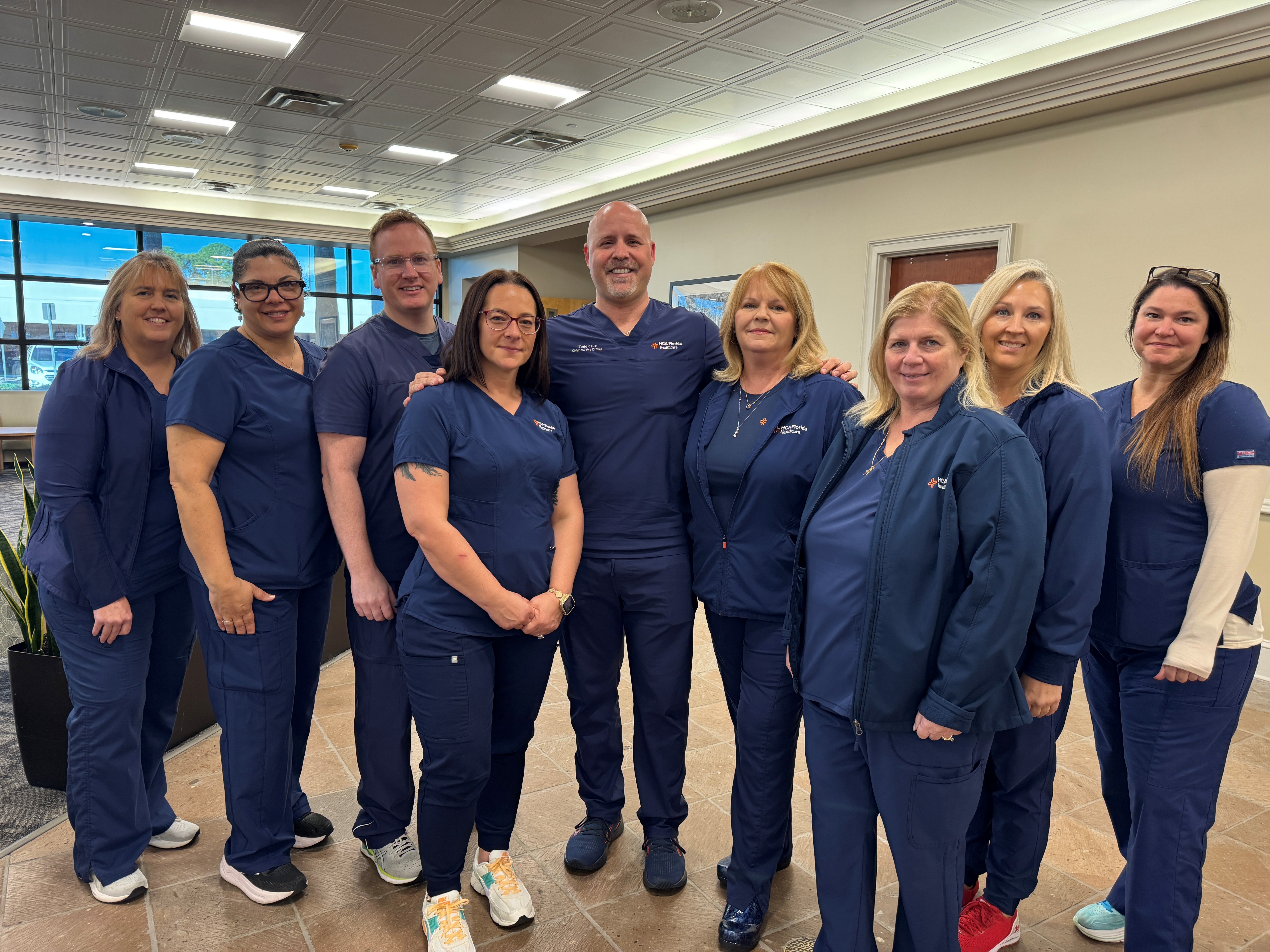 Group of male and female nurses stand smiling.