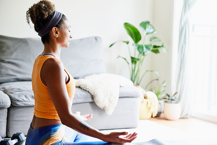 A woman practices yoga while in a seated position with her eyes closed.