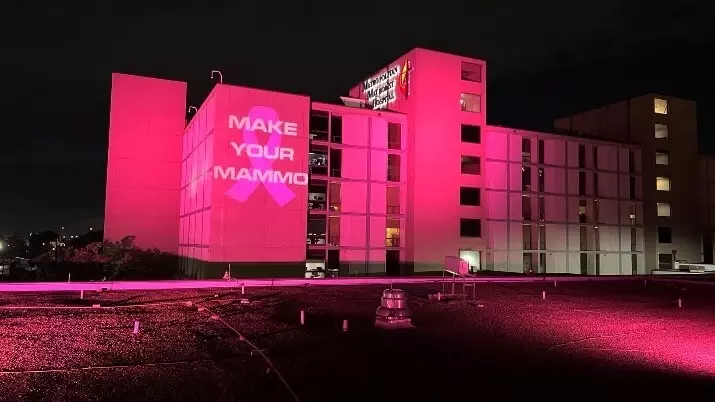 The exterior of Methodist Hospital at night awash in pink light with the phrase "Make Your Mammo" projected on the wall.