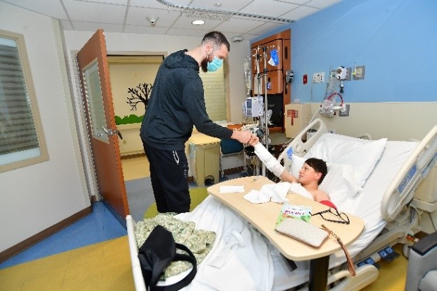 Spurs forward Sandro Mamukelashvili shaking hands with a patient.