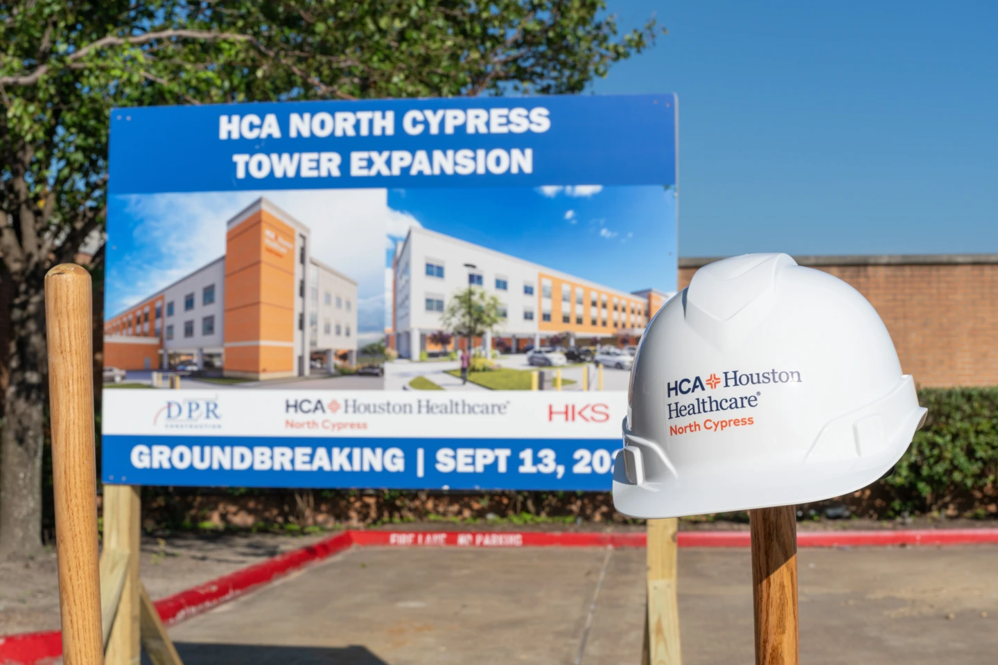 Rendering of new patient tower on a sign with a hard hat in front of it; "HCA North Cypress tower expansion groundbreaking September 13"