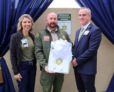 Lacey Page, Justin Rowan and Peter Hemstead smile while standing together in front of the newly unveiled parking spot in honor of Sheriff Deputy Timothy Corlew.