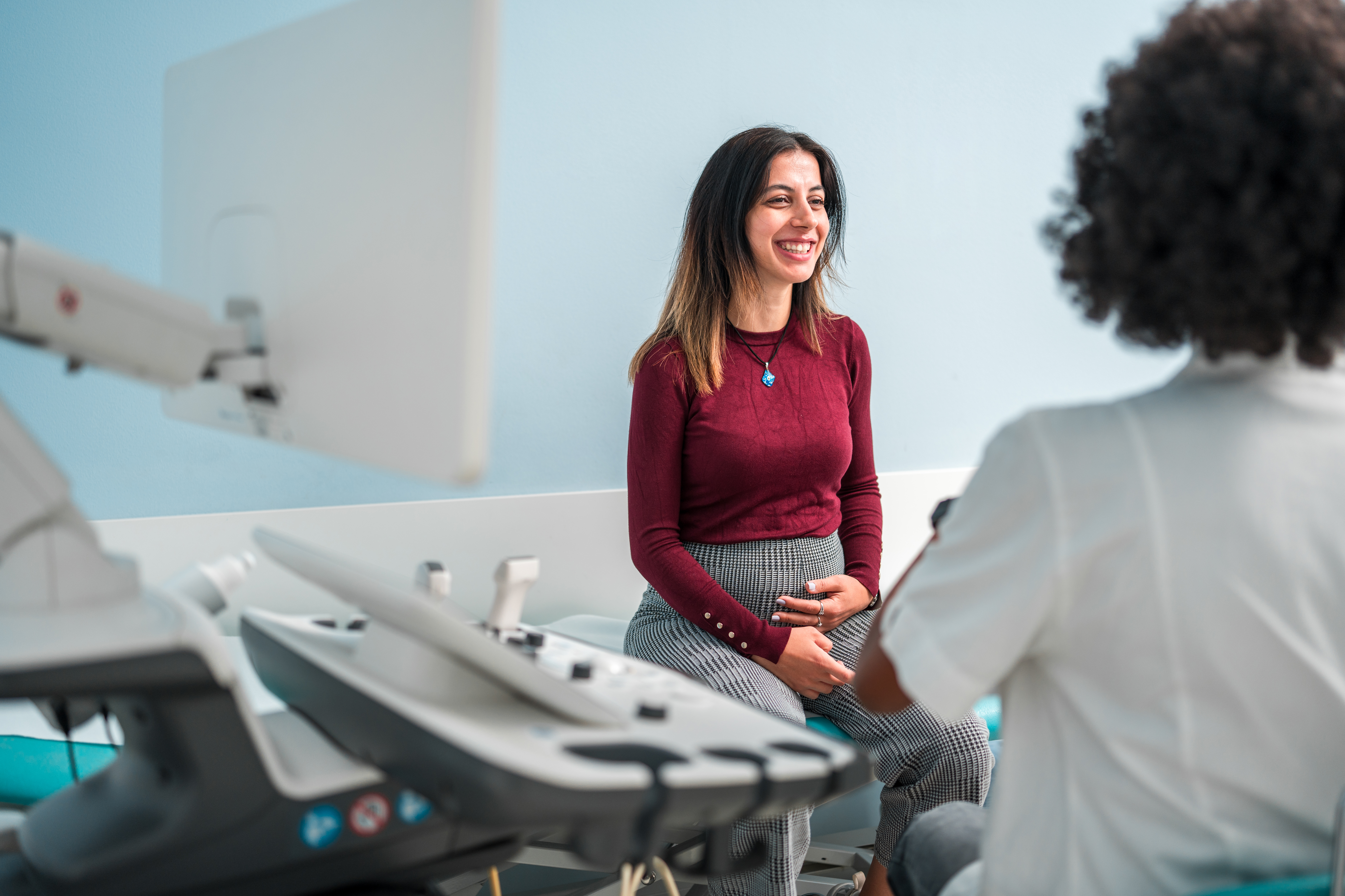 Pregnant woman holding her belly while talking with a doctor.